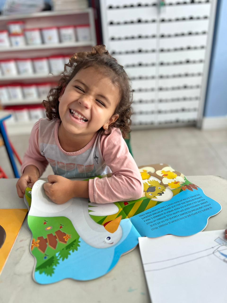 Criança sorrindo enquanto lê livro infantil no Colégio Futura Infantil em Jundiaí-SP