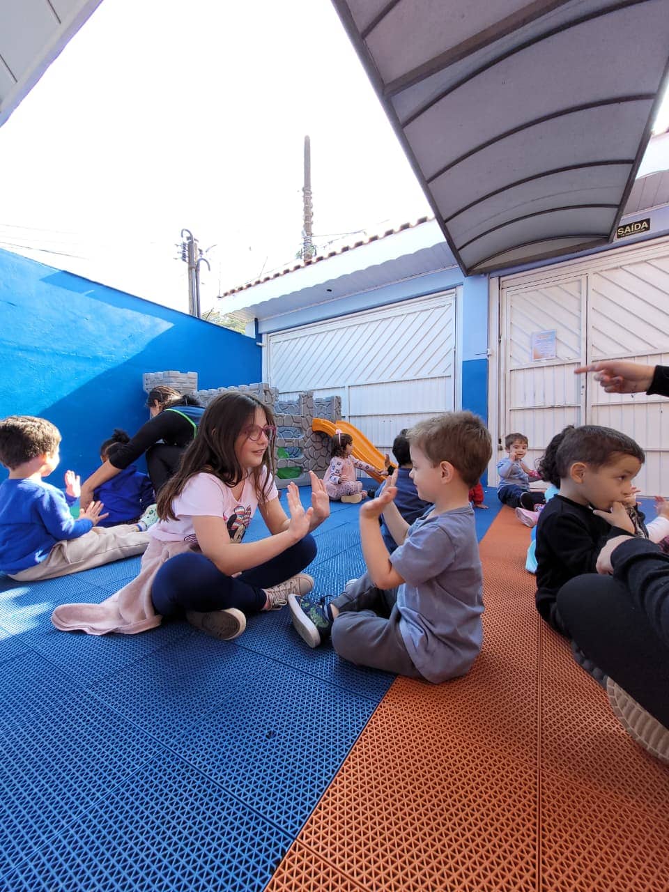 Crianças brincando em dupla no pátio do Colégio Infantil Futura, em atividade de socialização.