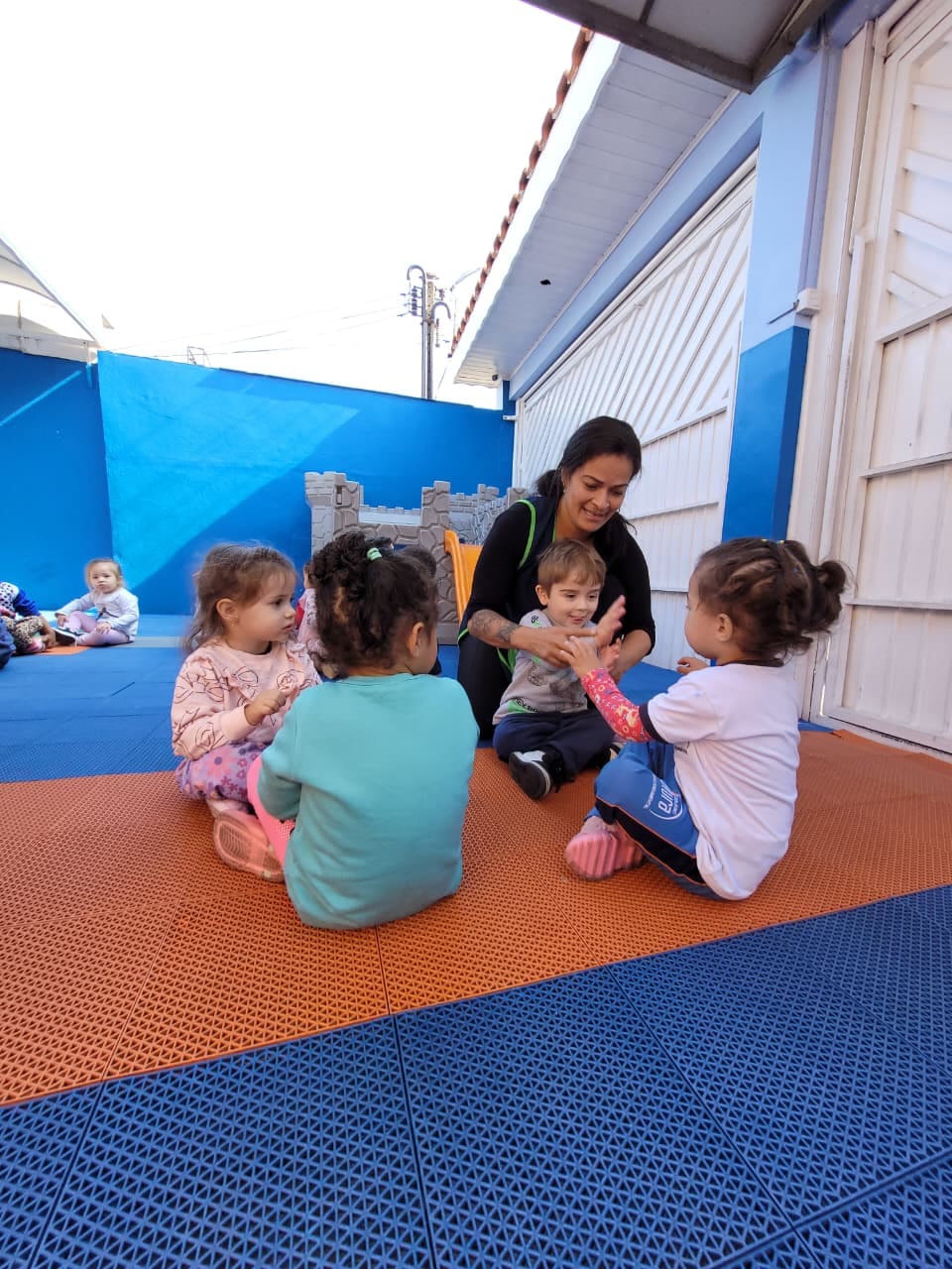 Crianças em atividade educativa com professora no pátio do Colégio Infantil Futura.