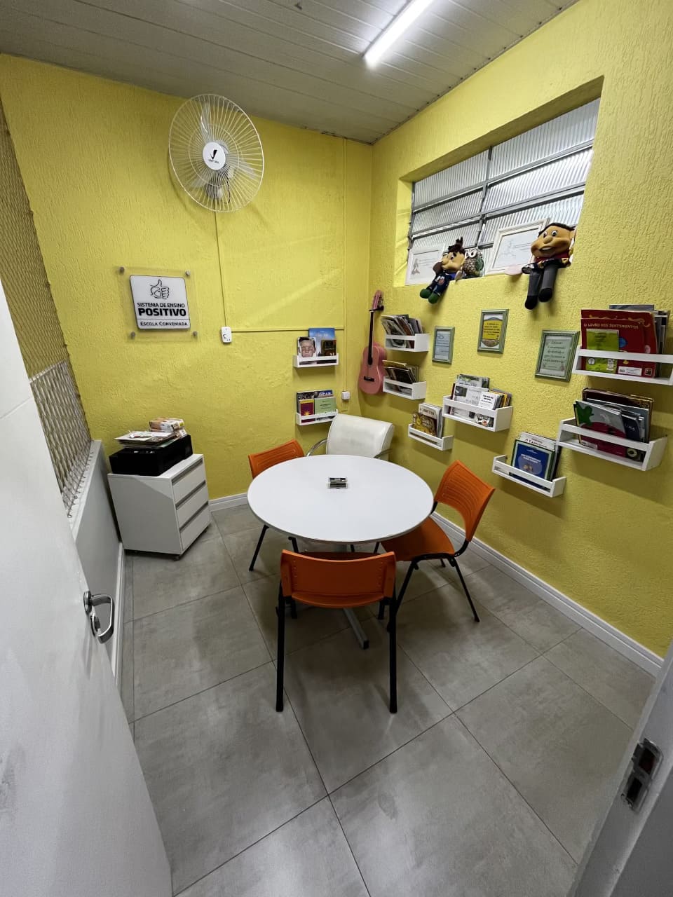 Sala pedagógica do Colégio Futura Infantil em Jundiaí com mesa redonda, cadeiras coloridas e estantes de livros.
