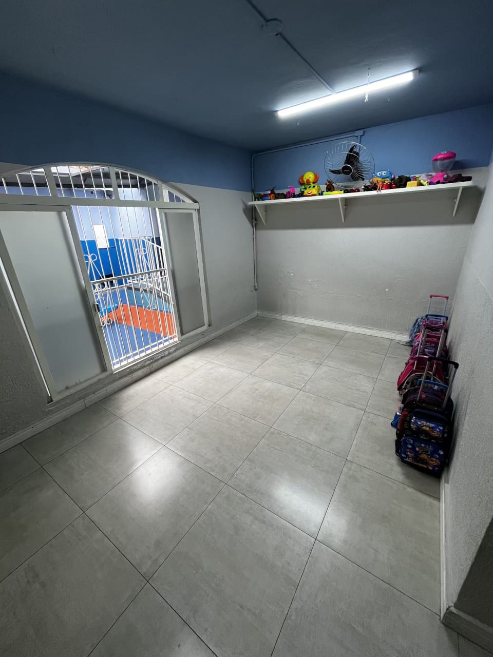 Sala de apoio do Colégio Futura Infantil com prateleira de brinquedos e mochilas organizadas.