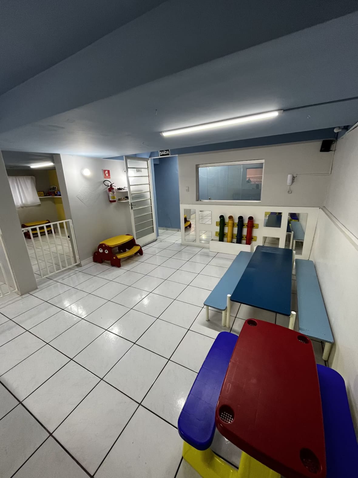 Espaço interno do Colégio Futura Infantil com mesas coloridas e ambiente preparado para atividades.