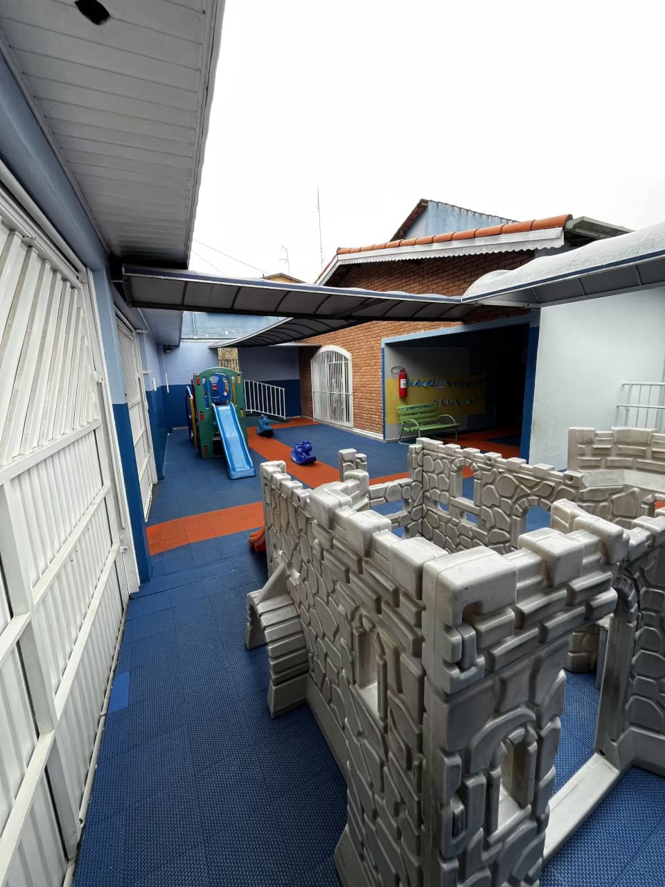 Área externa do Colégio Futura Infantil em Jundiaí com escorregador, castelinho de brinquedo e piso emborrachado.