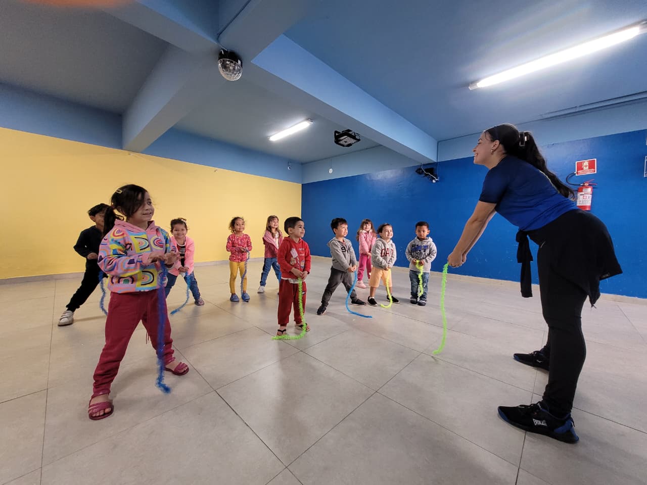 Professora de Arte e Movimento no Colégio Futura Infantil liderando uma atividade lúdica com crianças usando adereços em Jundiaí.