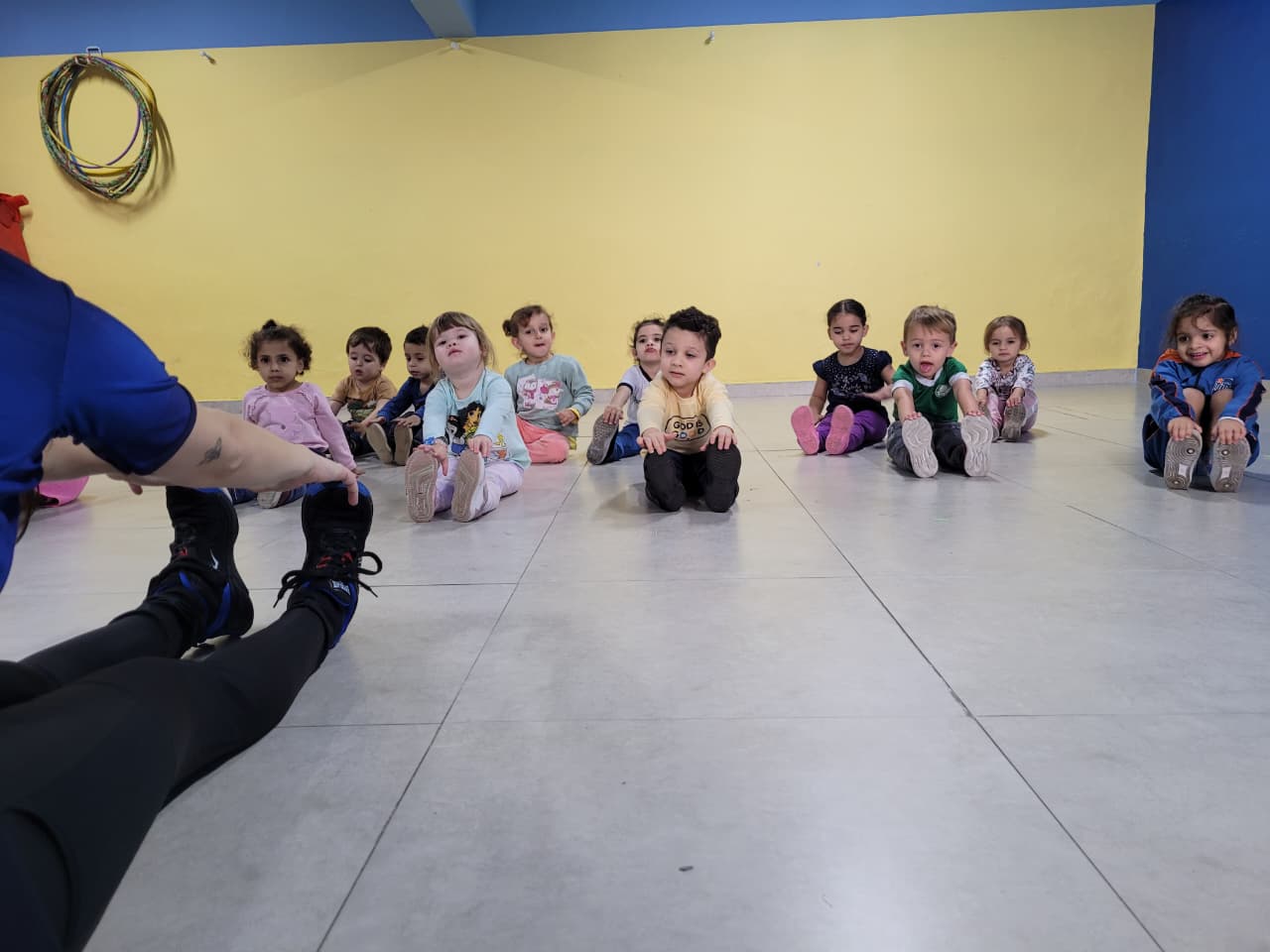 Crianças do Colégio Futura Infantil de Jundiaí fazendo alongamento com a professora durante a aula de Arte e Movimento.