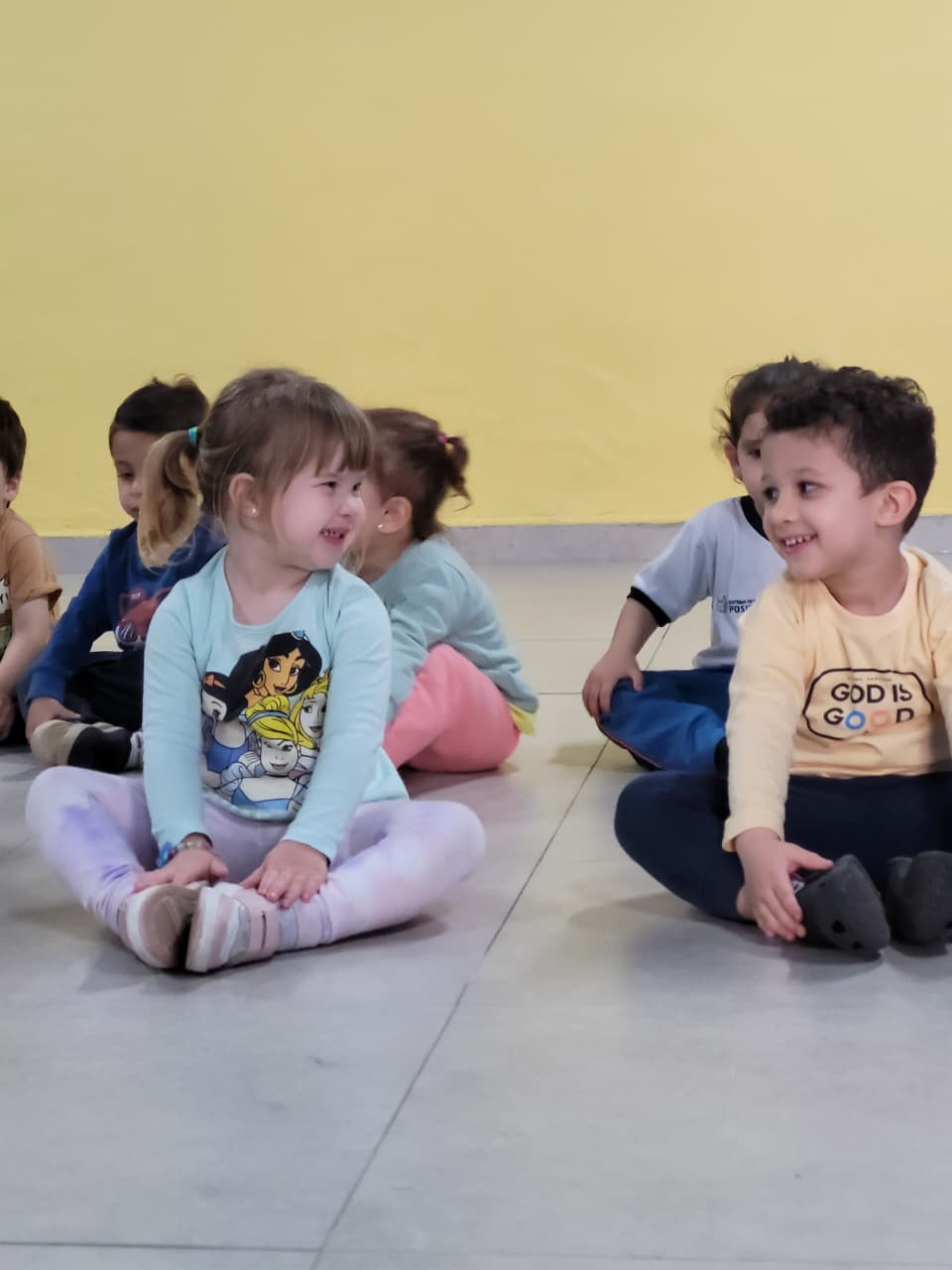 Crianças do Colégio Futura Infantil em Jundiaí, participando da aula de Arte e Movimento, sentadas e sorrindo.