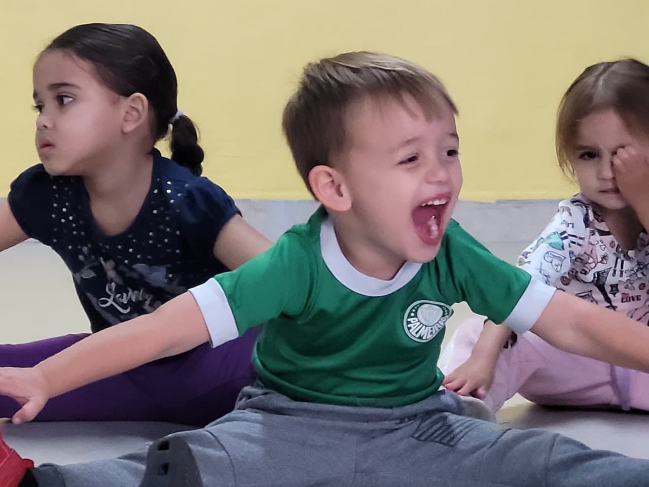 Criança sorrindo e se alongando durante a aula de Arte e Movimento no Colégio Futura Infantil.
