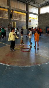 Crianças brincando com bambolês na quadra durante a 6ª Festa da Família do Colégio Futura 2025.