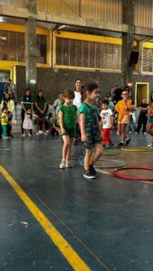 Crianças brincando com bambolês na quadra durante a 6ª Festa da Família do Colégio Futura 2025.