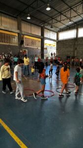 Crianças brincando com bambolês na quadra durante a 6ª Festa da Família do Colégio Futura 2025.