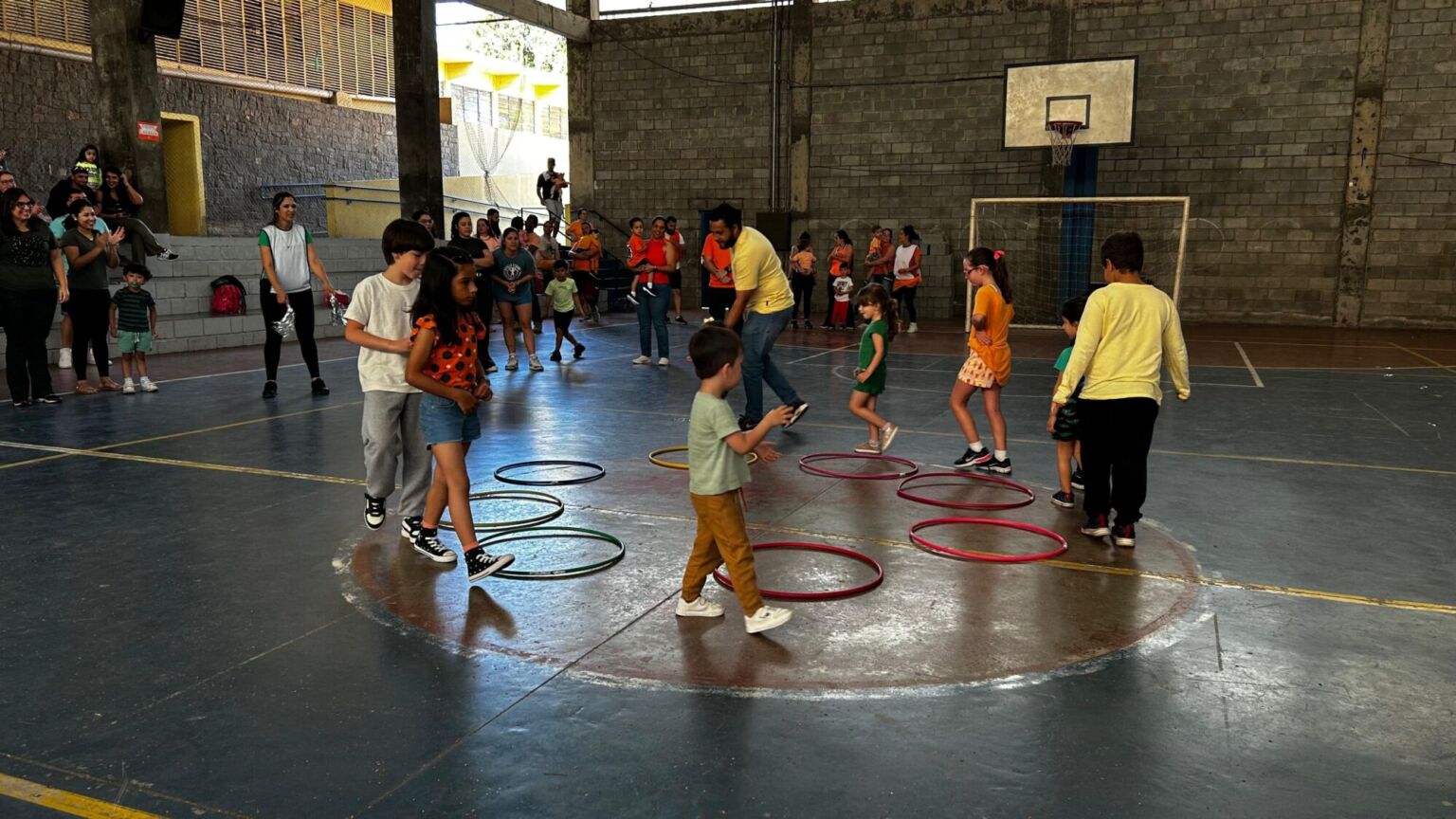 Crianças brincando com bambolês na quadra durante a 6ª Festa da Família do Colégio Futura 2025.