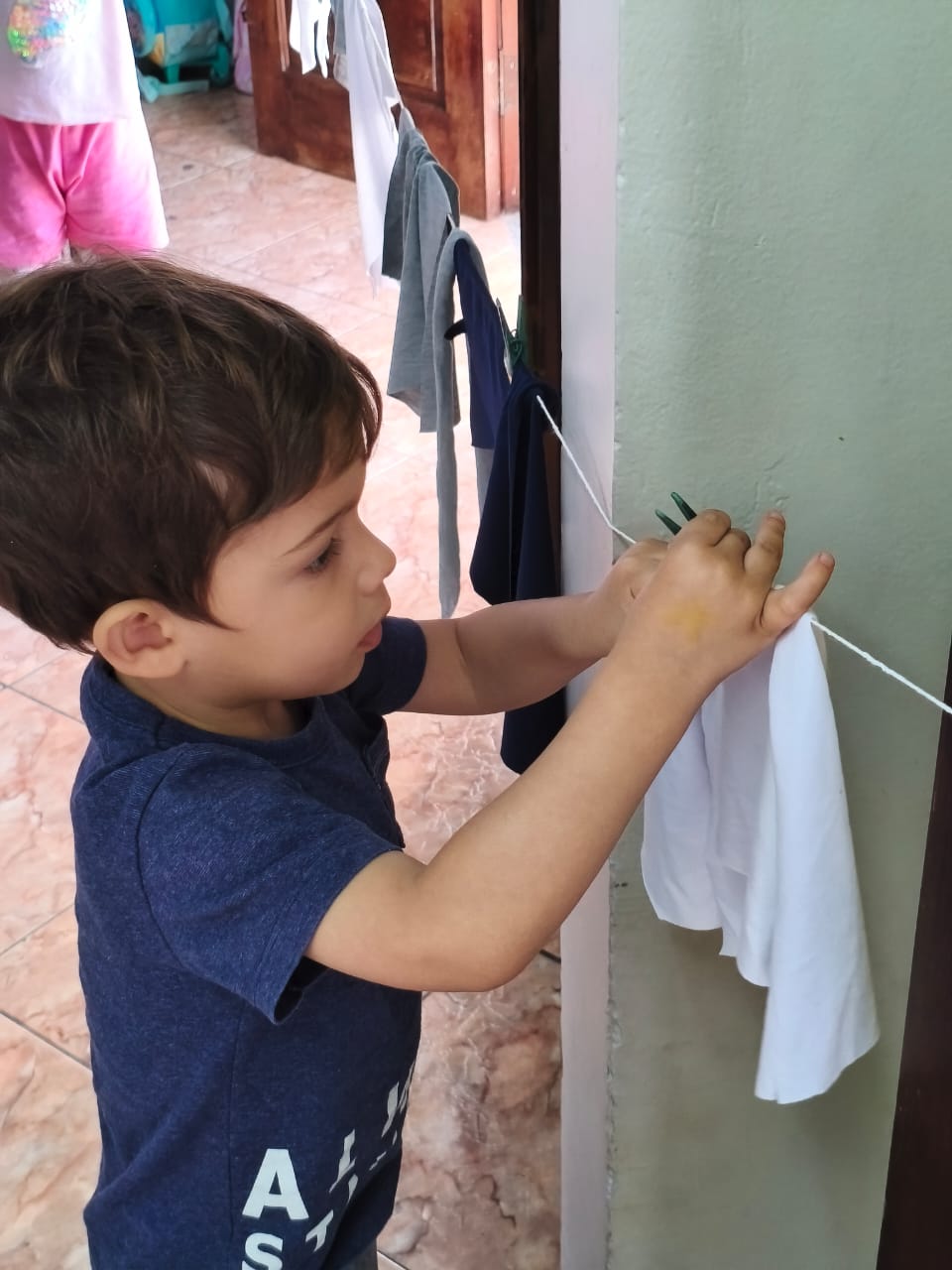 Criança pendurando uma roupa no varal em uma atividade de autonomia do projeto "Pequenas Ações, Grandes Transformações" no Colégio Futura Infantil em Jundiaí.