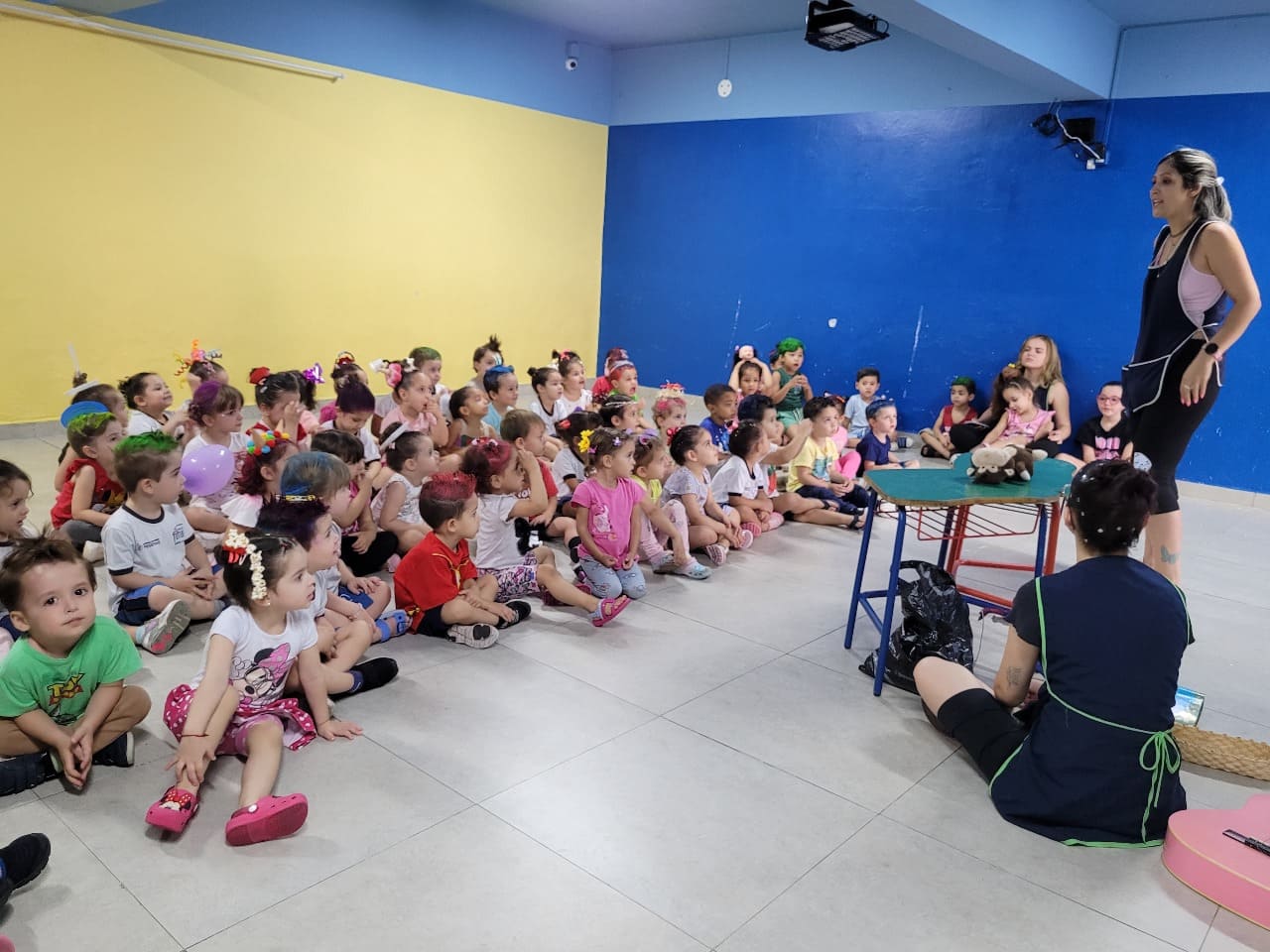 Grande grupo de crianças em roda assistindo a uma apresentação de professoras - Colégio Futura Jundiaí.