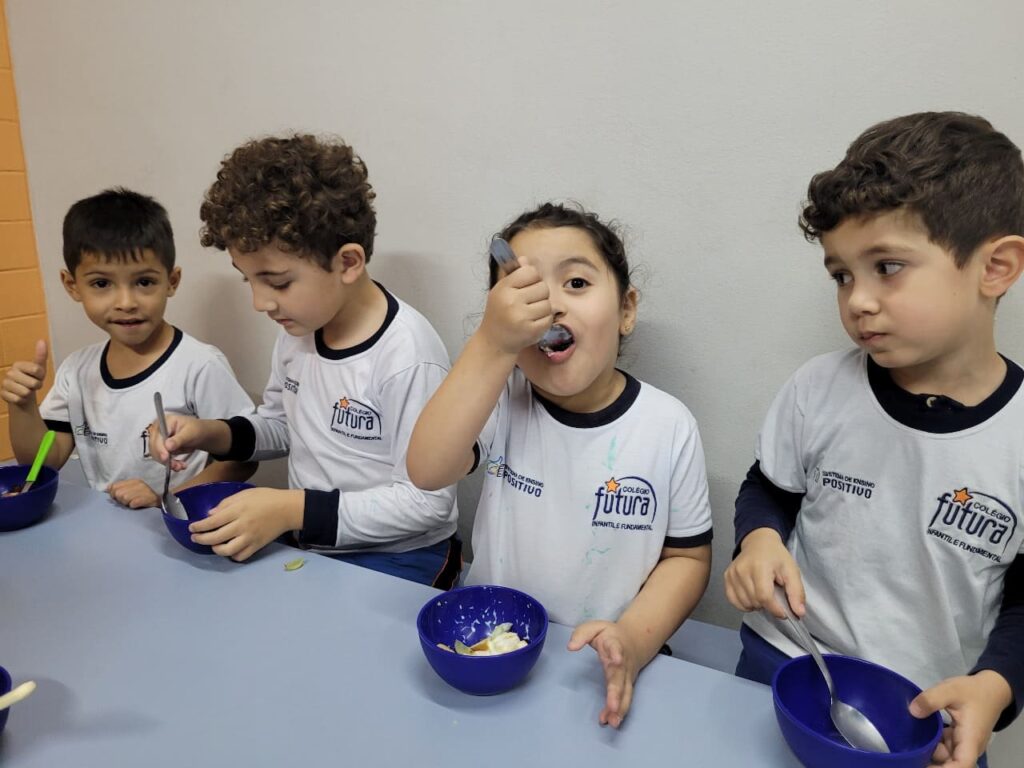 Crianças do Colégio Futura Jundiaí comendo salada de frutas e dando "joinha" em vivência de alimentação saudável.