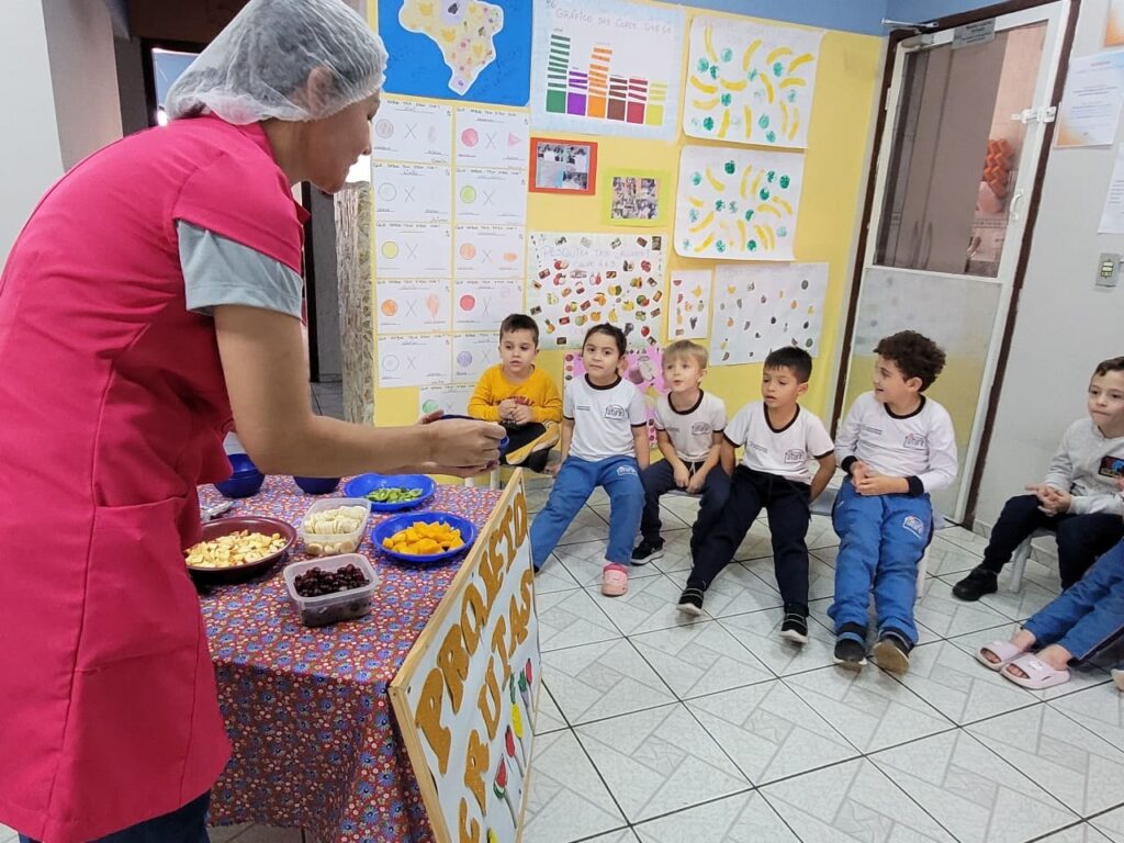 Nutricionista Ana Paula Silva falando com crianças em Jundiaí sobre frutas e alimentação saudável no Colégio Futura.