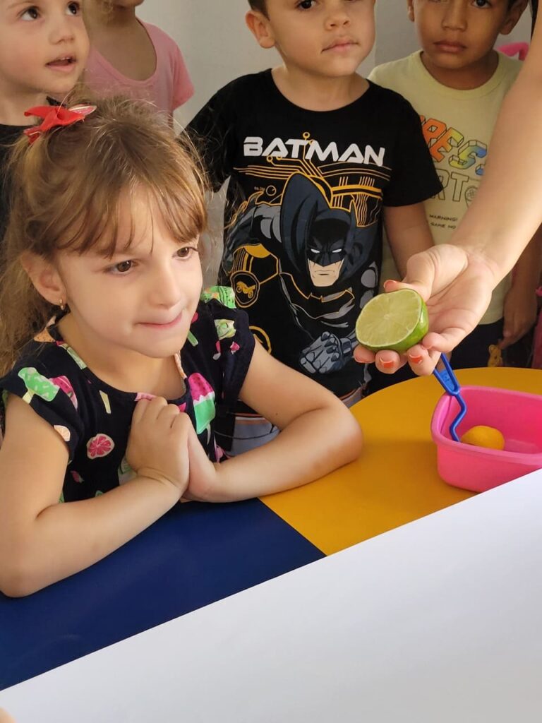 Criança do Colégio Futura Infantil Jundiaí observando um limão cortado em aula sobre frutas e vivência sensorial.