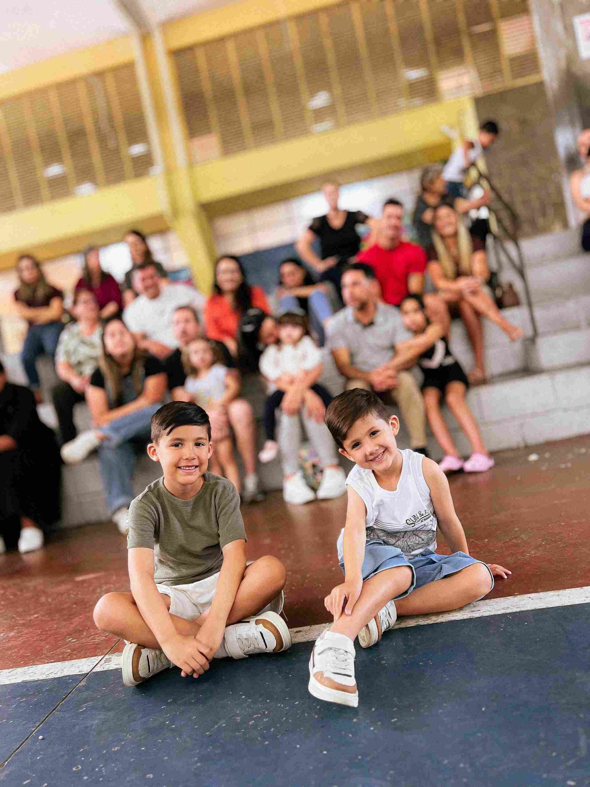 Duas crianças sorrindo na plateia, com o público de pais ao fundo, no Sarau 2025 do Colégio Futura Infantil Jundiaí.