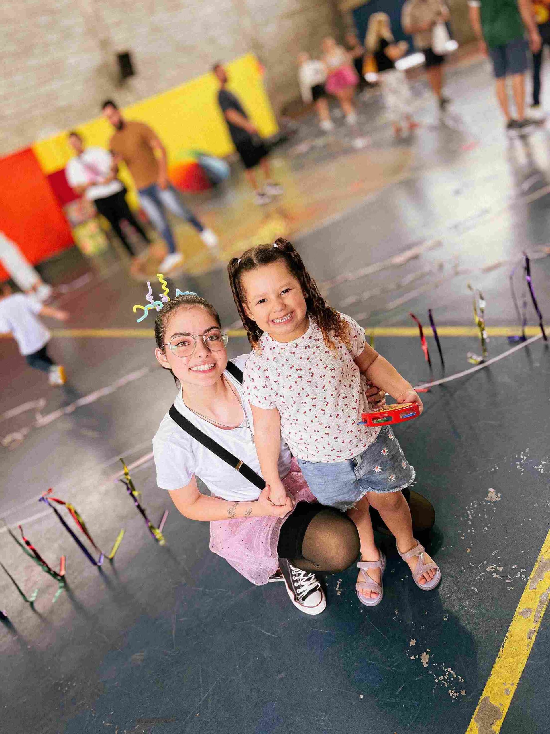 Professora e aluna sorrindo juntas, com um instrumento musical, durante o Sarau 2025 do Colégio Futura Infantil Jundiaí.