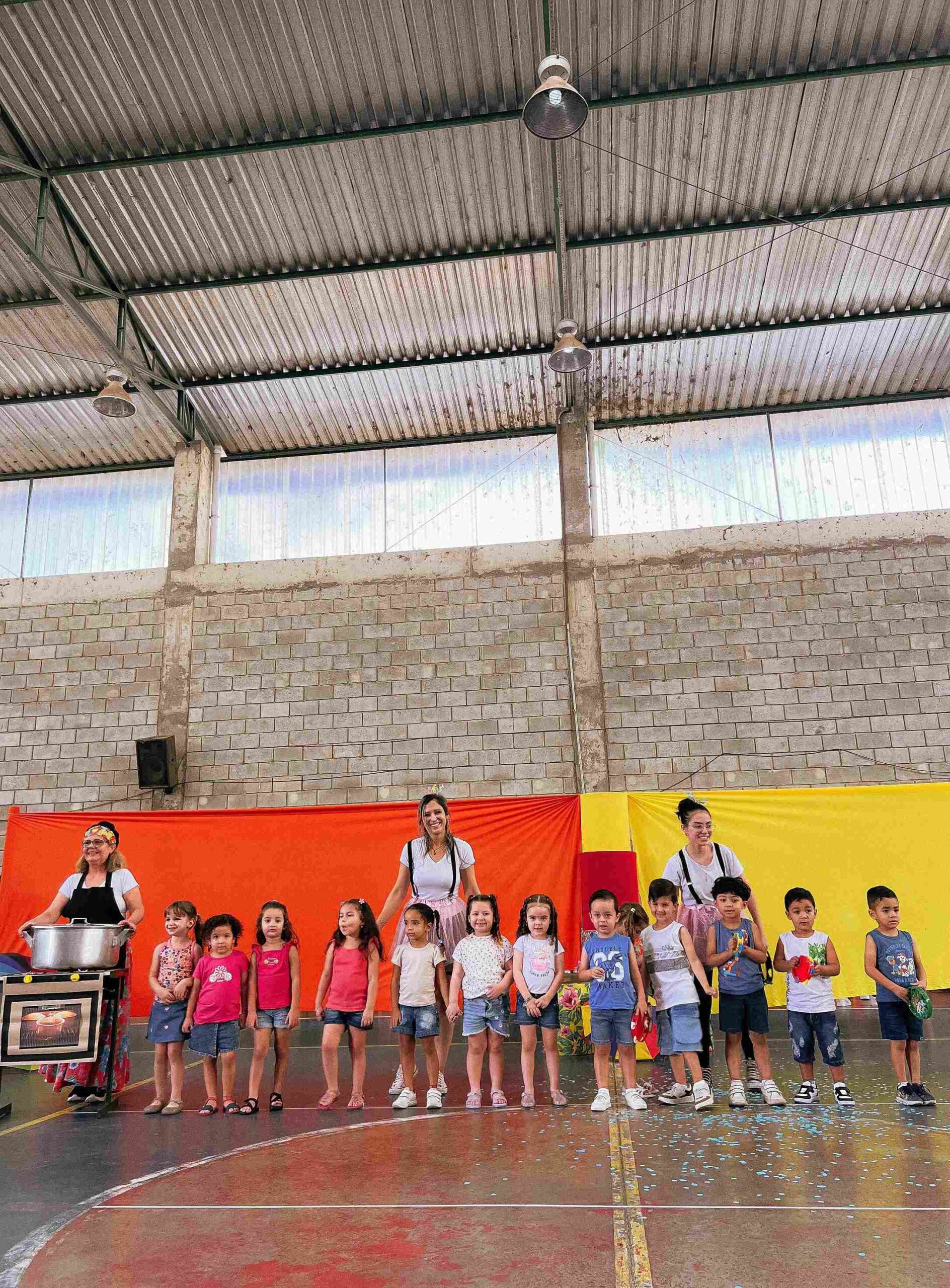 Grupo de crianças e professoras no palco do Colégio Futura Infantil Jundiaí, após a apresentação do Sarau 2025.