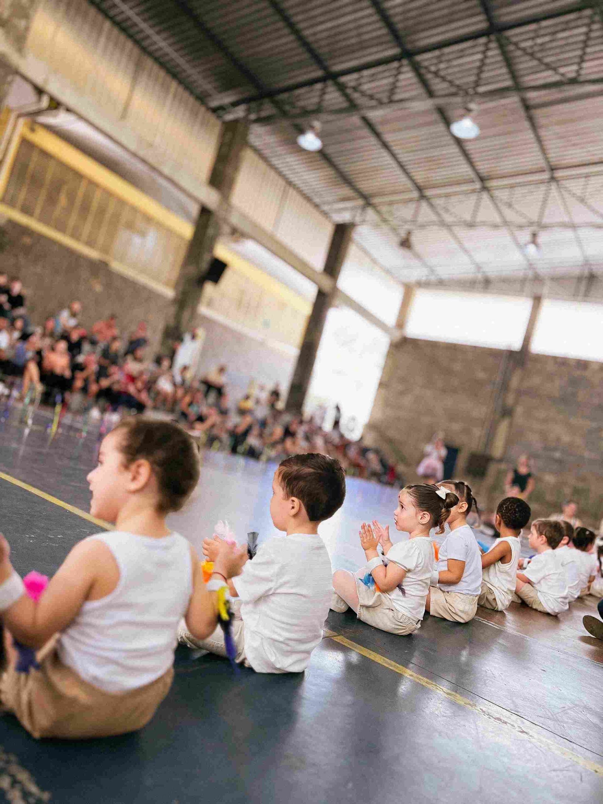 Grupo de crianças do Colégio Futura Infantil sentadas e aplaudindo a apresentação no Sarau 2025 em Jundiaí.
