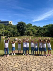 Alunos do Colégio Futura Infantil Jundiaí Grupo 3 posando com braços levantados em frente ao lago no Jardim Botânico de Jundiaí SP.