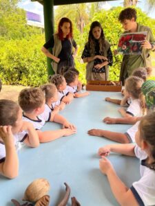 Alunos do Colégio Futura Infantil Jundiaí Grupo 3 em mesa de estudo com guias/educadores, aprendendo sobre sementes e botânica no Jardim Botânico de Jundiaí.