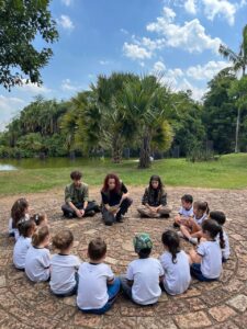 Alunos do Colégio Futura Infantil Jundiaí sentados em círculo ouvindo história contada por educadores no Jardim Botânico de Jundiaí SP, em atividade pedagógica do Grupo 3.