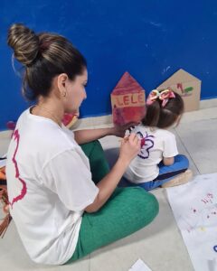 Adulto pinta borboleta roxa em camiseta de criança no evento Entre Cores e Afetos do Colégio Futura Infantil em Jundiaí SP