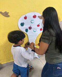 Criança e adulto pintam frutas em árvore de papel no evento Entre Cores e Afetos do Colégio Futura Infantil em Jundiaí SP