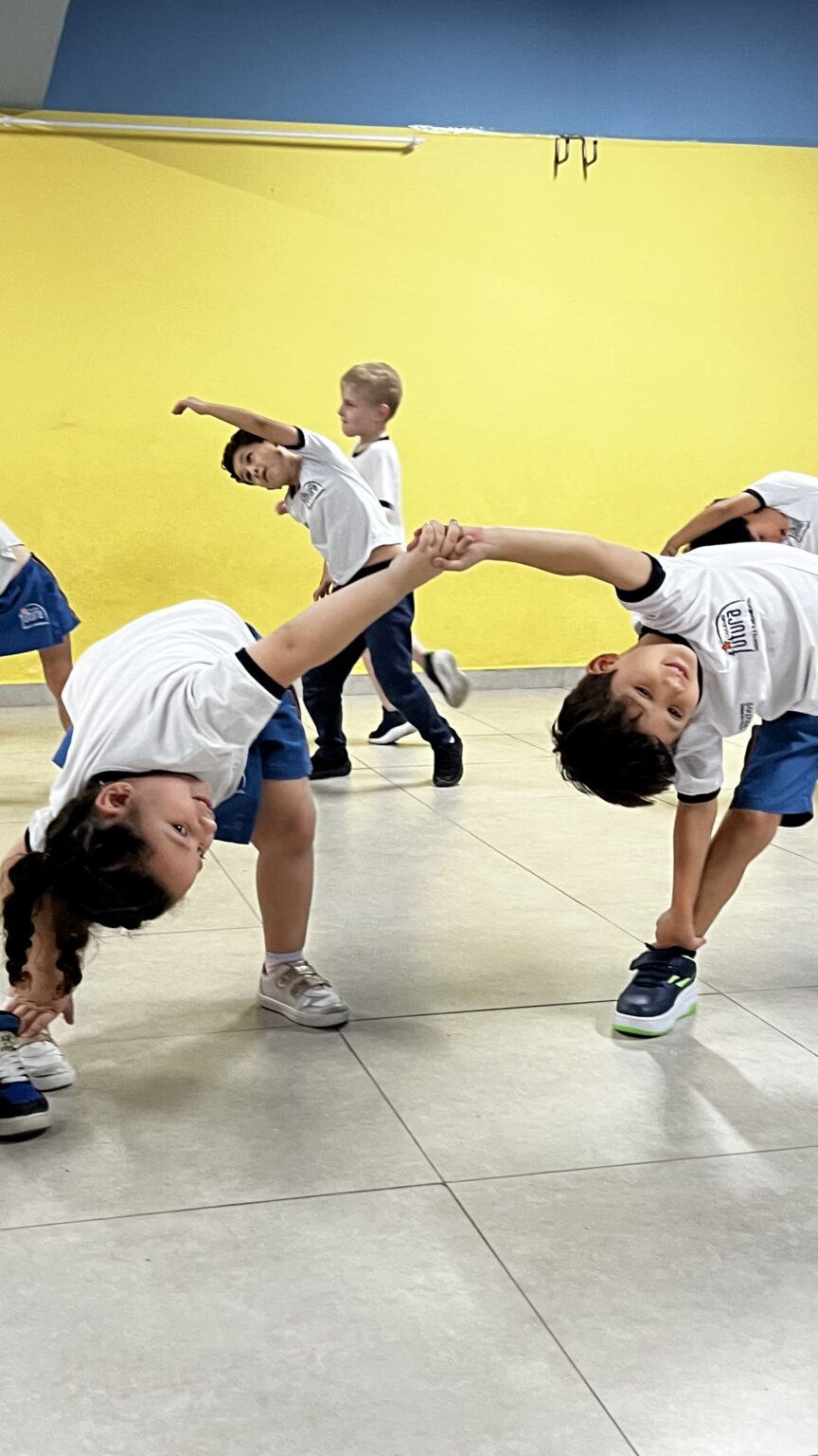 Crianças em dupla realizando alongamento de dança no Colégio Futura Infantil em Jundiaí-SP.