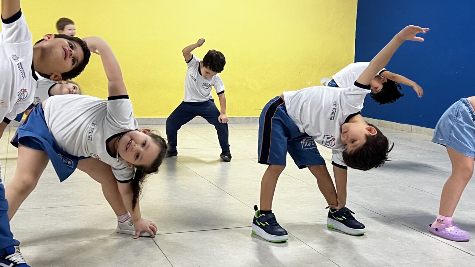 Crianças realizando alongamento lateral em aula de dança no Colégio Futura Infantil em Jundiaí-SP.